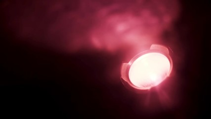 Poster - Close up of red spotlight blinking in complete darkness. Action. Red soffit shimmering in the dark room, being turned on isolated on black background.