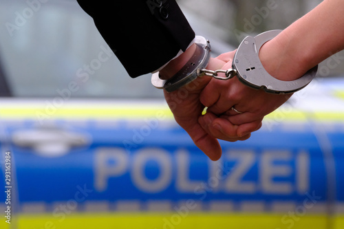 Fotomural Die mit Handschellen aneinander gefesselten Hände eines jungen Ehepaares vor ein