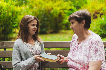 Daughter sharing a book with her mother in the park