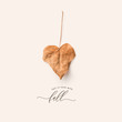 minimalist conceptual autumn / fall concept or greeting card with single heart-shaped dry leaf and calligraphic text reading fall in love with fall on a cream colored background - top view / flat lay