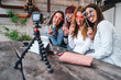 Group of young millennials women vloggers watching in the camera while having fun with fake glasses and mustache during a live show