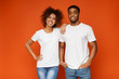 African american man and woman smiling on orange background