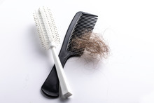 A Closeup View Of A Hairbrush And Comb, Isolated Against A Clean White Background With A Clump Of Brunette Hair, Alopecia And Baldness Concepts.