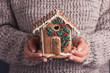 woman hands in sweater holds gingerbread house