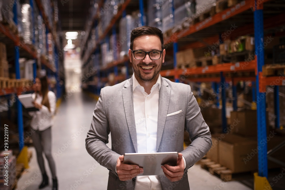 Cheerful and successful middle aged caucasian manager businessman holding tablet computer in large warehouse organizing distribution. Business people. CEO visiting warehouse. - obrazy, fototapety, plakaty 