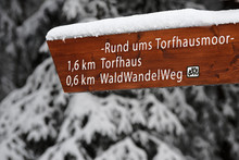 Snow Covered Wooden Directional Signpost With Labeling "Way Around Torfhaus Moor" And Distance To Torfhaus And The "Forest Hiking Way"