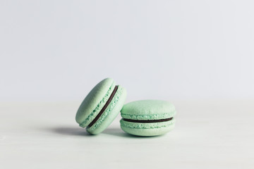 Two French macarons on a white wooden table. Mint macarons. White background.