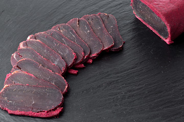 Wall Mural - Cured meat on a slate board. Close-up of basturma sliced into pieces.