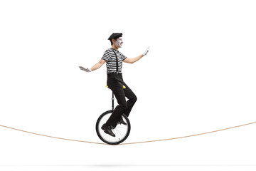 Poster - Pantomime man riding a unicycle on a rope and balancing with hand