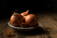 Brown Onions And Shallots In A Stone Bowl, On A Rustic Timber Background.