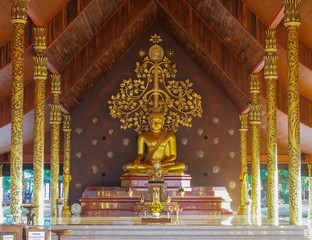 Ubon Ratchathani, TH - November 2, 2018: Big Golden Buddha Statue Sitting in the pavilion Behind him is a beautiful golden tree. At Sirinthon Wararam Phu Phrao Temple.