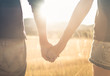 © kieferpix - Couple holding hands walking together in sunset nature setting.