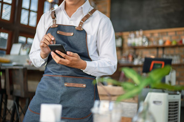 Waiter using touch pad or smart phone to send customer order in the restaurant. Modern wireless technology for retaurant or coffee shop.