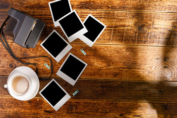 Top view of blank photographs next to a camera on a wooden table. The concept of pleasant memories. Place for text. Copy space.