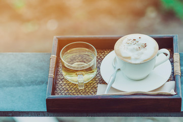 Hot coffee in a white cup and Chinese tea for a relaxing break for farmers in the afternoon on the terrace in the kale farm.