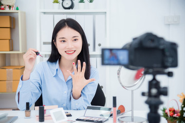 Beautiful asian girl talking about her nail polish color in front of camera to recording vlog video live streaming at her shop.