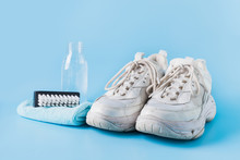 Dirty White Sneakers With Special Tool For Cleaning Them On Blue.