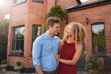 Excited Young Couple Standing Outside New Home Together