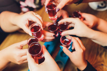 Close Up Shot Of Group Of People Clinking Glasses With Wine Or Champagne In Front Of Bokeh Background.