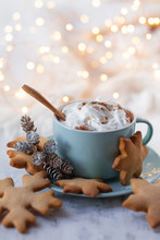 Hot Winter Drink: Chocolate With Whipped Cream In Blue Mug. Christmas Time. Cozy Home Atmosphere, White Background. Homemade Gingerbread Cookies, Cones, Candle, Lights As Decor. Holiday Festive Mood
