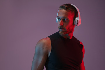 Sports man posing isolated listening music with headphones.