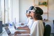 © Mangostar - Excited users testing VR simulator. Man and women wearing VR headset, sitting at workplaces with laptops, turning face up. Virtual reality simulation concept