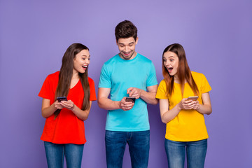 Wall Mural - Portrait of nice attractive lovely charming cheerful cheery glad guys wearing colorful t-shirts jeans surfing web site browsing 5g app news game free time isolated over violet lilac background