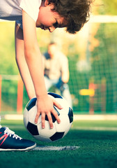 Wall Mural - Little boy with his dad playing football on soccer pitch. kid football player prepairing to take a shot on a football field