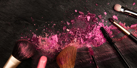 Wall Mural - A panorama of makeup brushes and lipstick with crushed cosmetics, shot from the top on a dark background with a place for text, a beauty design template