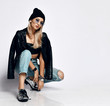 © Dmitry Lobanov - Young grunge style girl in torn jeans, leather top, leather jacket and chrome boots sitting squatting at free copy space