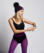 © Dmitry Lobanov - Stylish sporty blonde woman in sport bodysuit, leggings and purple winter hat is looking at her smart watches