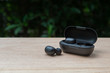 Black true wireless earbuds with power bank case on the wooden table with green background