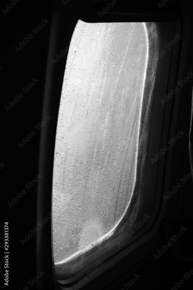drops of rain on the airplane window during the flight black and white - obrazy, fototapety, plakaty 