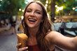 © Drobot Dean - Beautiful young ginger woman take selfie by camera eat ice cream.