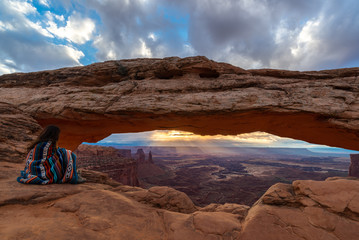 Woman watching the sunrise at Mesa Arch, Canyonlands National Park, Utah, USA  