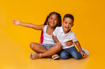 Wall Mural - Adorable little sister and brother sitting on floor and cuddling