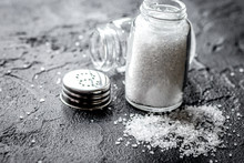 Salt In Glass Bottle Scattered On Dark Table Background