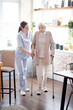 Caregiver assisting woman walking with crutches