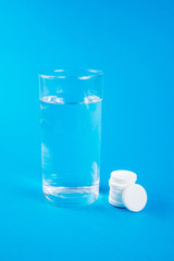 Wall Mural - Clear glass of water and soluble effervescent tablets isolated on blue background. The concept of treatment and prevention of viral diseases. Help with depression and insomnia.To drink liquid medicine