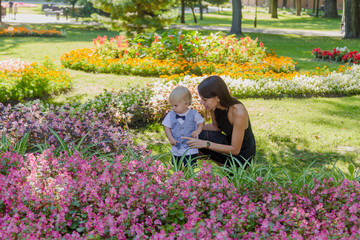 Young mother with her little son in a flower bed.