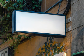 Wall Mural - Blank white store signboard mockup. Empty shop signage mounted on the ancient wall. Street sign