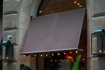 Wall Mural - Blank brown black awning over cafe windows mockup. Empty awning mounted on the ancient wall in european town.
