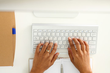 Hand of black woman type something with white wireless computer keyboard closeup