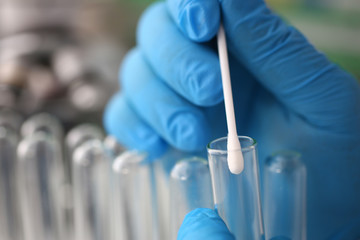 forensic scientist conducting criminal investigation aganist laboratory background. holds cotton swa