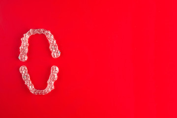 Top view of invisalign braces or invisible retainers on red background, new orthodontic equipment