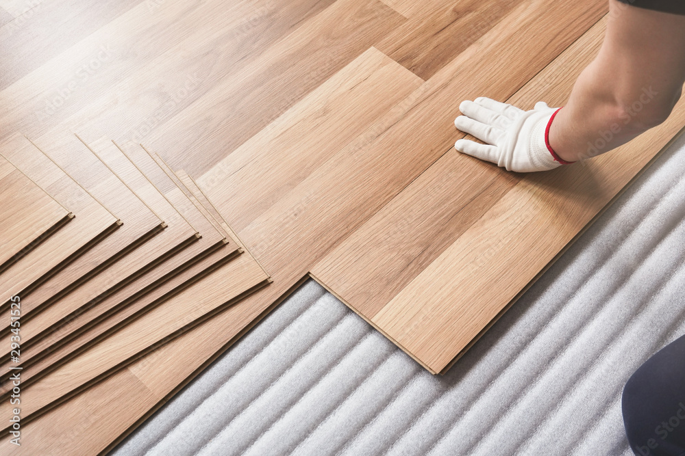 Installing laminated floor, detail on man hand in white glove fitting wooden tile, over white foam base layer - obrazy, fototapety, plakaty 