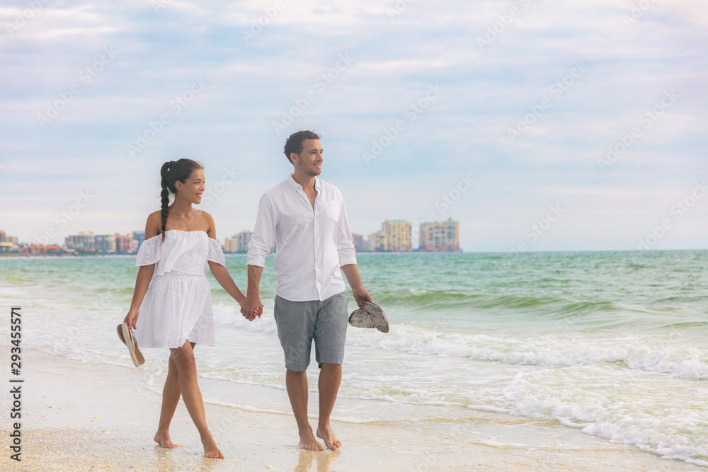 Beach couple romantic sunset walk Asian woman and Caucasian man relaxing  walking on Florida vacation beach travel holidays wearing white dress and  linen clothes. Happy interracial relationship. Stock Photo | Adobe Stock