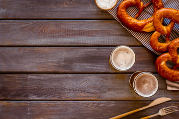 Wall Mural - Octoberfest table background. Pretzels and beer glasses on dark wooden background top view frame copy space