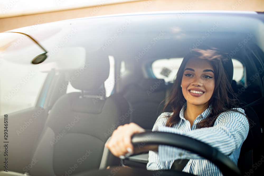 Beautiful young happy smiling woman driving her new car at sunset. Woman in car. Close up portrait of pleasant looking female with glad positive expression, woman in casual wear  driving a car - obrazy, fototapety, plakaty 