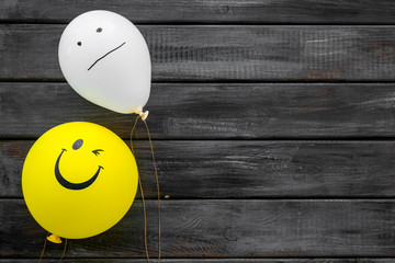 Wall Mural - Treat depression concept. Balloons with frustrated and smiling faces on dark wooden background top view copy space